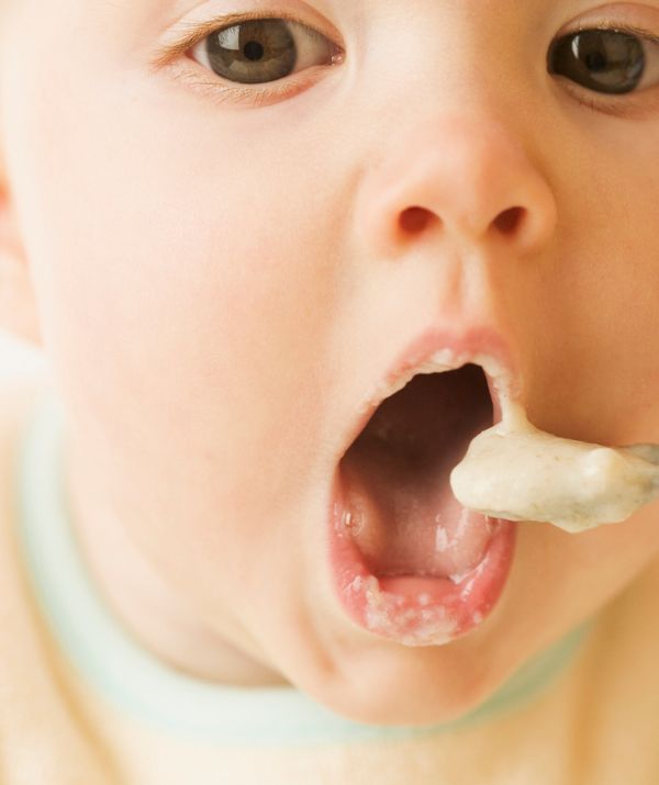 Close up for baby's face about to eat a spoonful of soft food