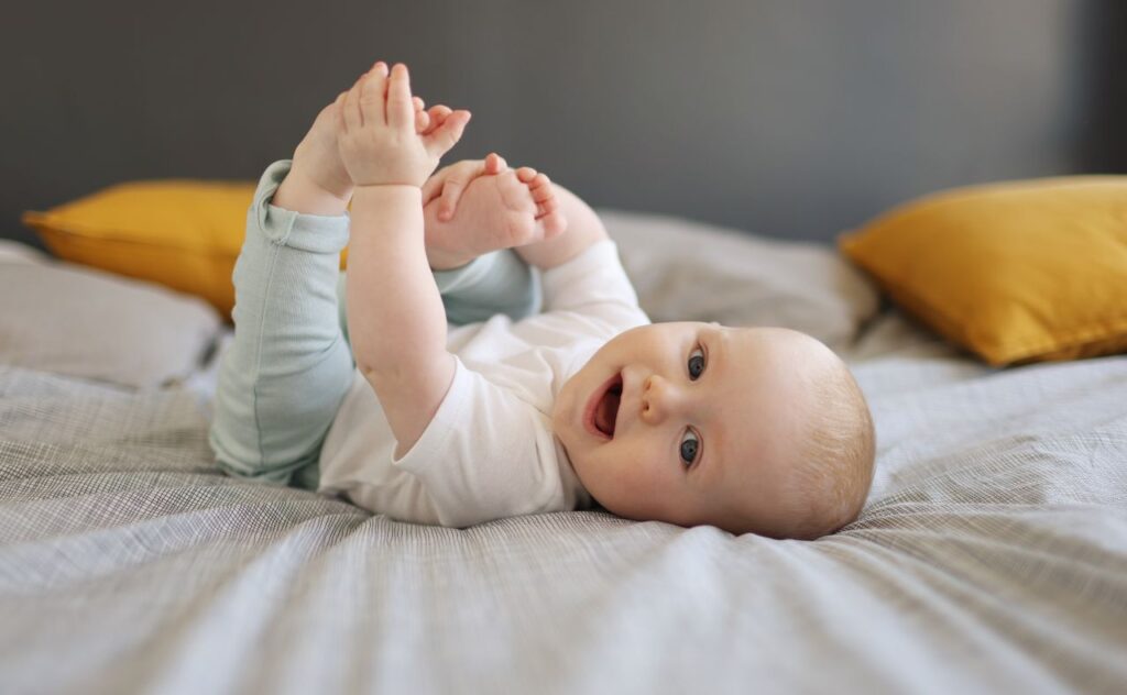 Baby vaccination: A 6 month old baby boy smiling, laying on a bed