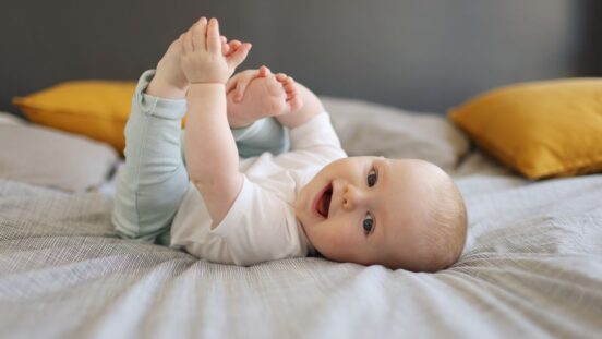 Baby vaccination: A 6 month old baby boy smiling, laying on a bed