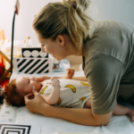 Women leaning over her baby on a change table