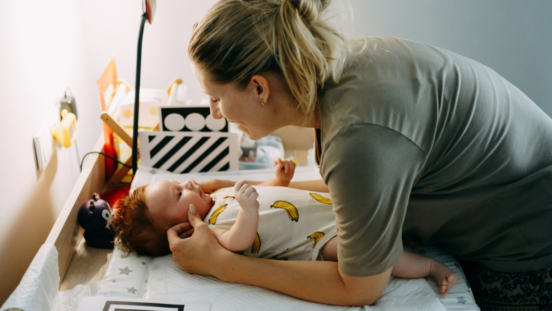 Women leaning over her baby on a change table