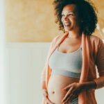 Pregnant woman at home looking through the window