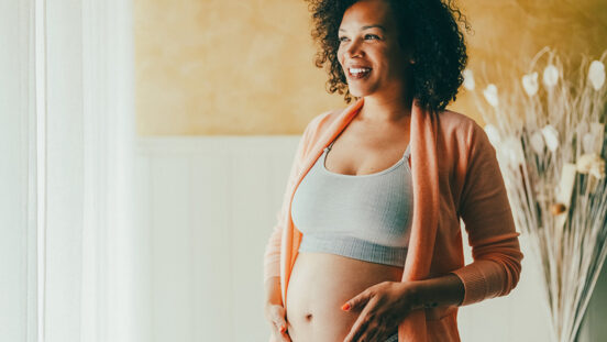 Pregnant woman at home looking through the window