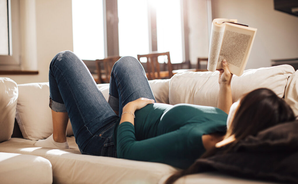 Pregnant woman reading a book while lying down.