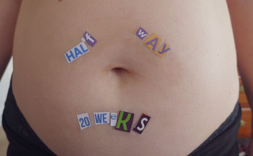 Close-up of a woman belly pregnant with wrote on top "Half Way - 20 weeks"
