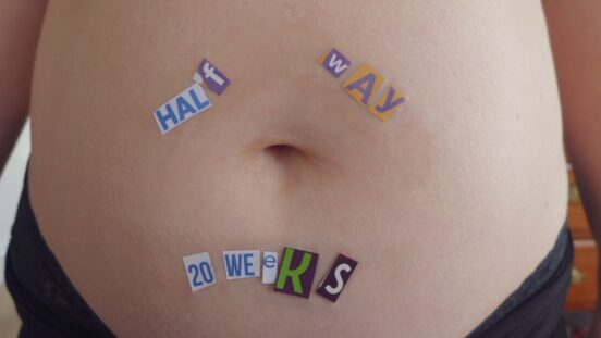 Close-up of a woman belly pregnant with wrote on top "Half Way - 20 weeks"