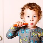 Baby teeth care: A toddler in his pyjamas brushing his teeth.