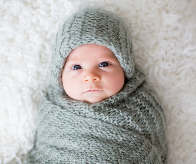Newborn infant wrapped in a knitted throw