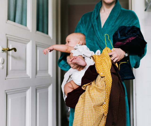 Tired mum in gown carrying baby and laundry