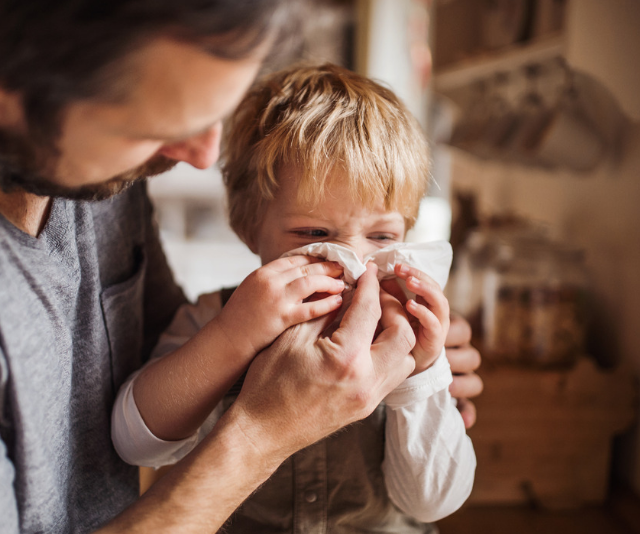 Father helping son blow his nose
