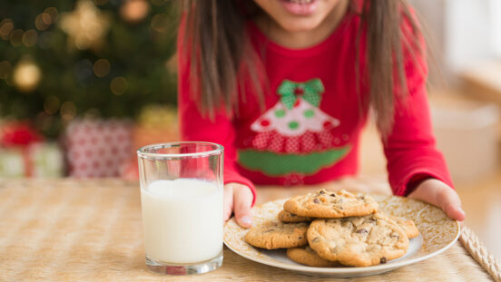 Hispanic girl setting out milk and cookies for Santa