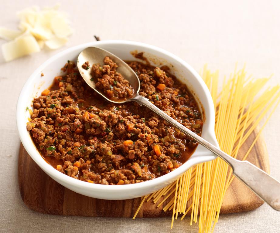 Bowl of bolognese next to spaghetti