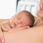 Mother laying in bed skin to skin contact with newborn