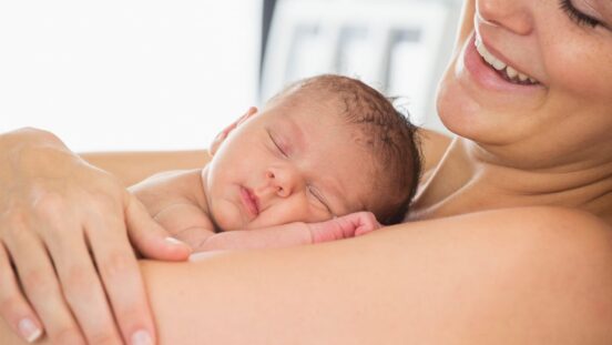 Mother laying in bed skin to skin contact with newborn