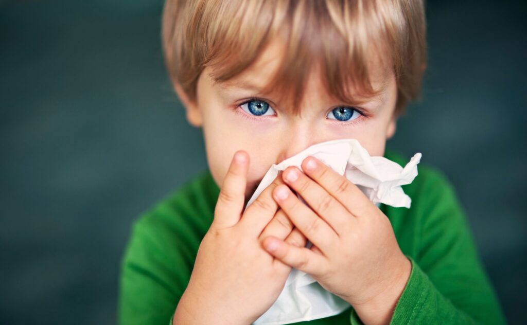 Portrait of a sick boy cleaning his nose