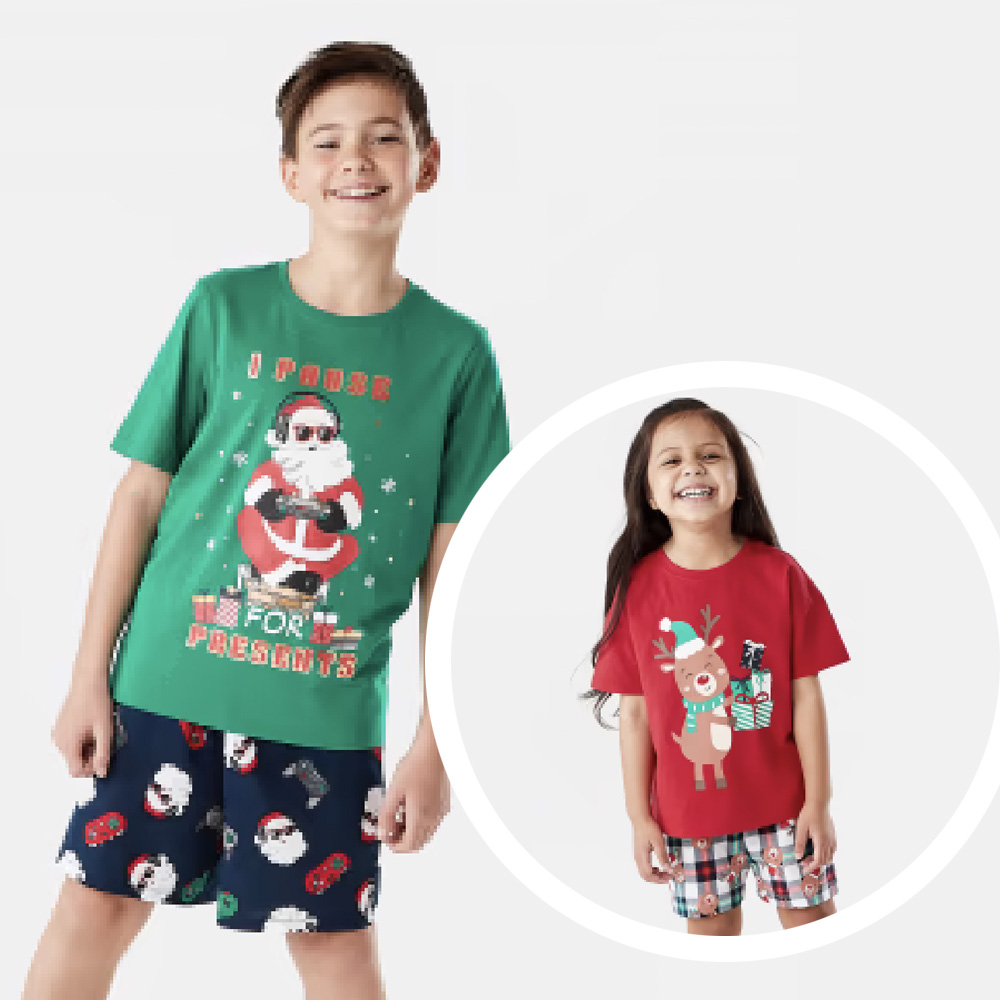 Tween boy wearing green Christmas short pyjamas, and little girl with long dair hair wearing red Christmas PJs