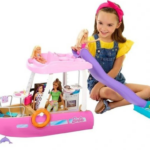 Girl in sitting on the floor playing with Barbie dolls and Barbie boat