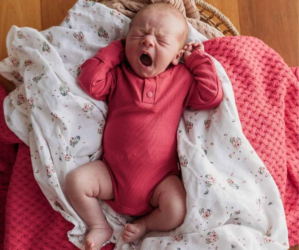 Yawning baby wearing Hibiscus Long Sleeve Organic Bodysuit