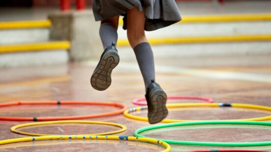 Little girl in school uniform jumping through hoops