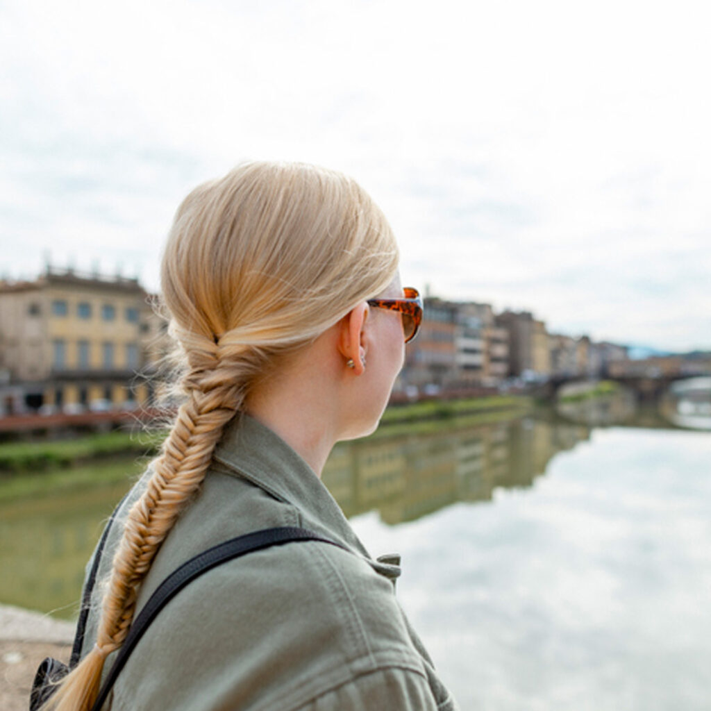 Woman travelling in Florence. She is looking away from the camera wearing sunglasses.
