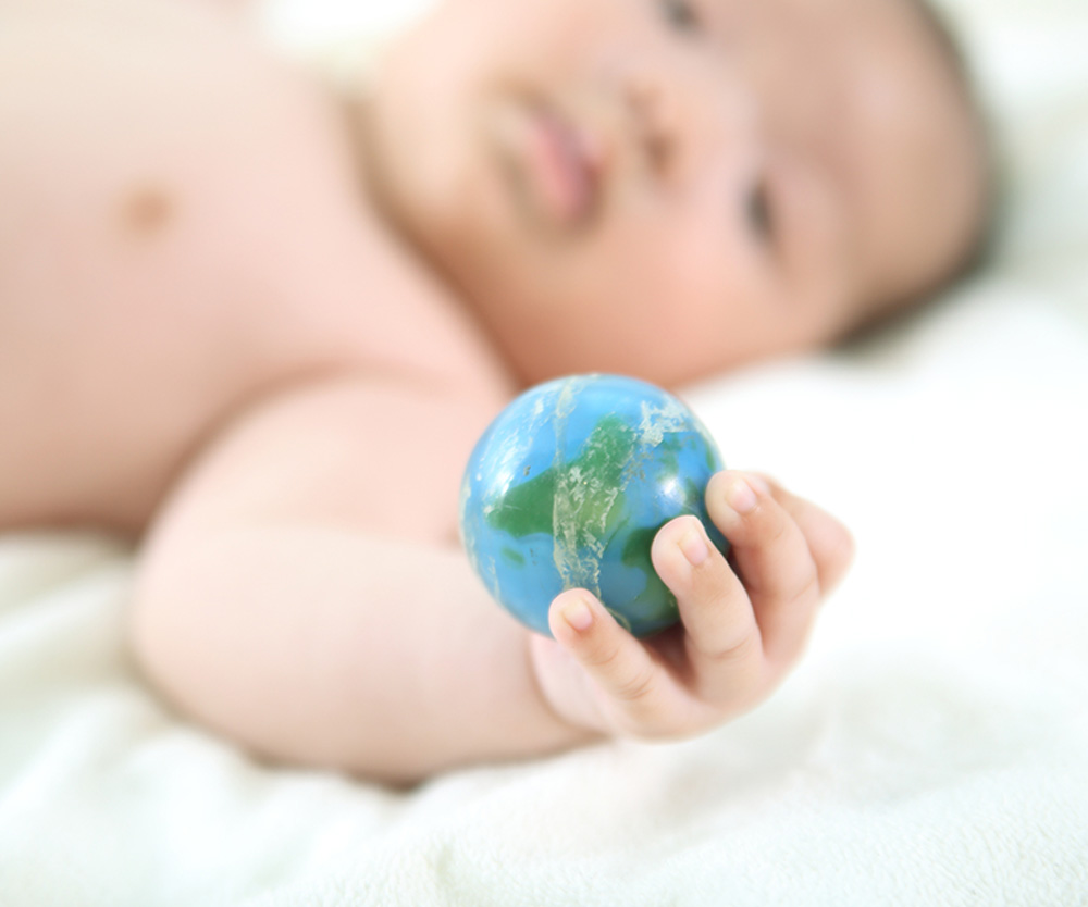 Close up of a baby's hand holding a small ball that looks like a globe