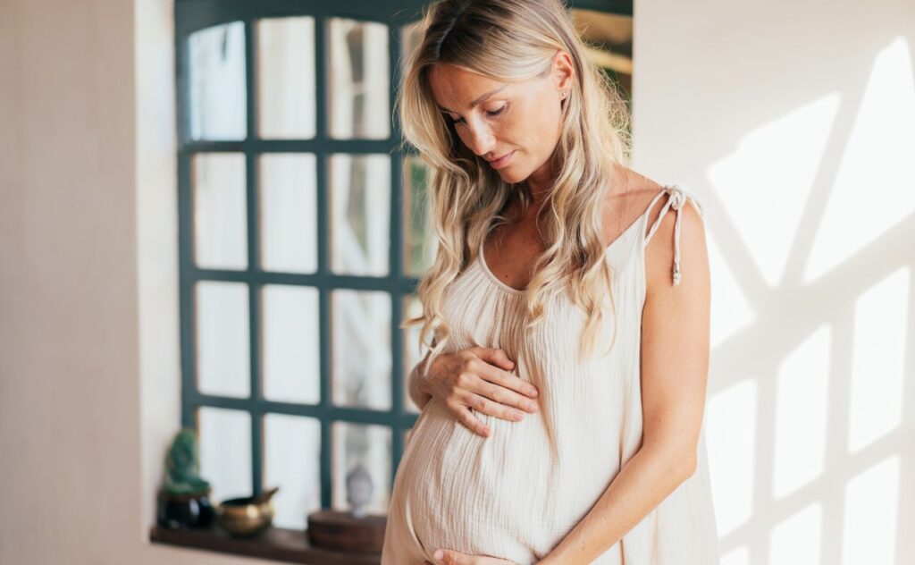 Blonde haired pregnant woman looking at her bump