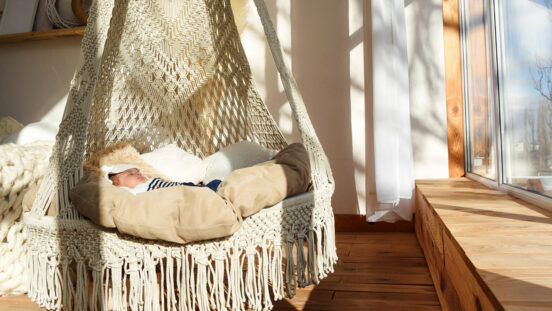 Baby sleeping in a circular hanging woven hammock bed