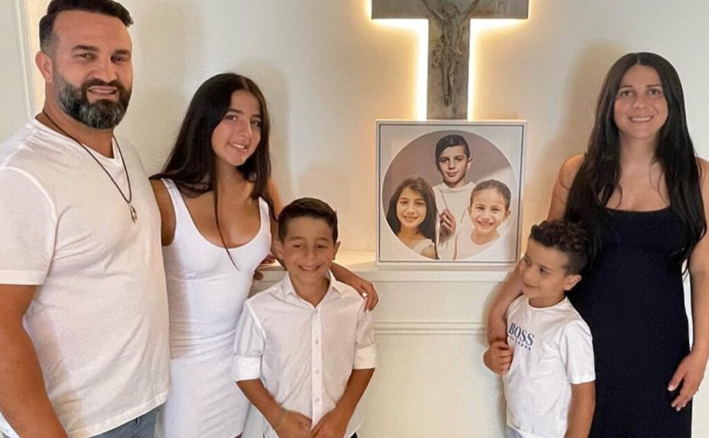 The Abdallah family stand alongside a photo of their three children who were killed in the horror crash