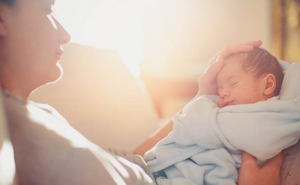 Soft focus image of father cradling sleeping newborn's head.