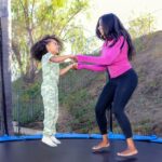 Woman jumping on a trampoline holding hands with a little girl