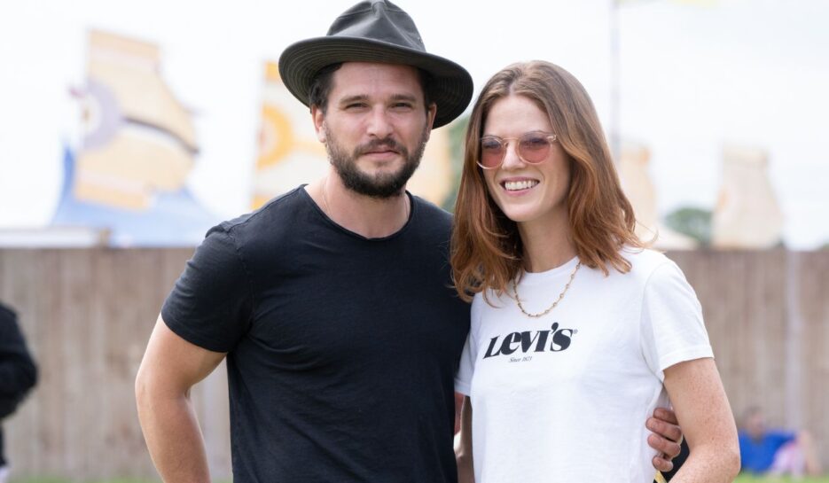 Kit Harington wears a black hat and black tshirt and stands with Rose Leslie who wears sunglasses and a white tshirt.