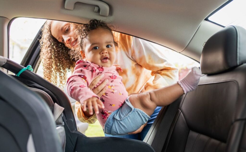 Mother putting baby in car seat