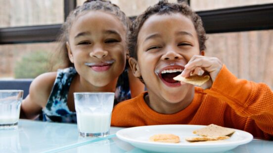 Two children enjoying milk and snacks