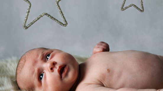 Newborn baby looking towards camera.