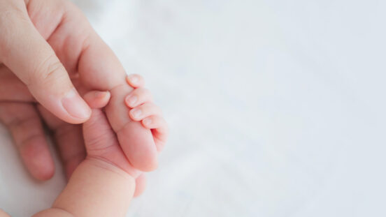 Newborn hand clutching an adult finger.