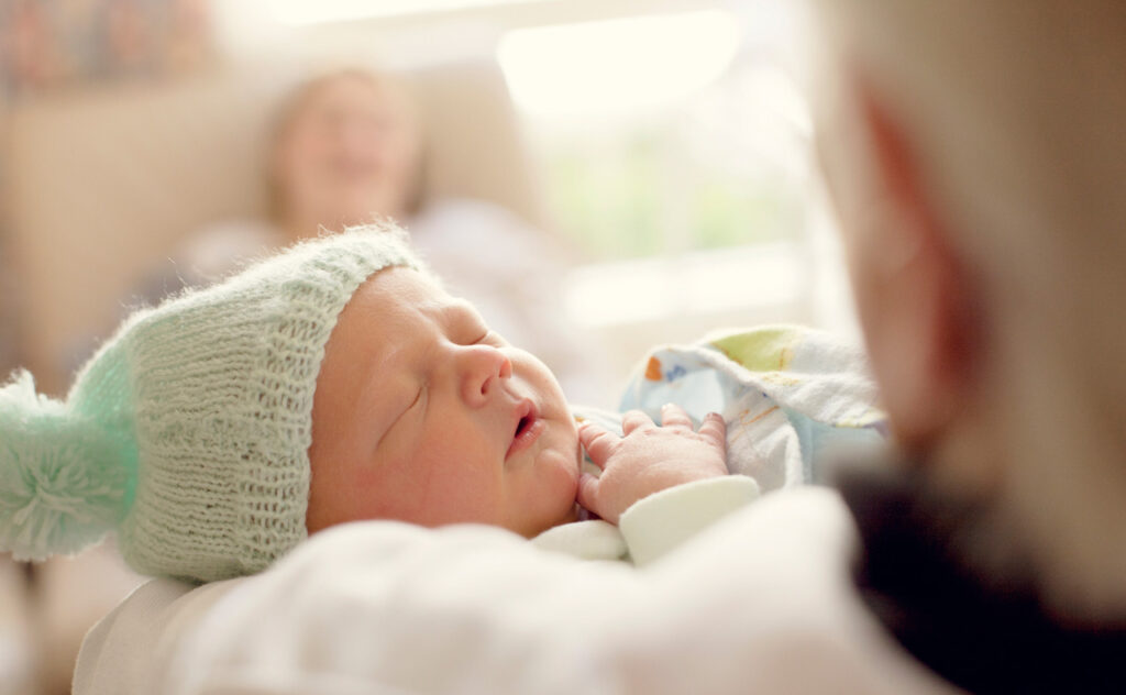 Sleeping newborn with mint coloured wooden beanie.