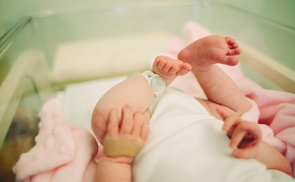 Newborns raised legs with hospital id on ankle.