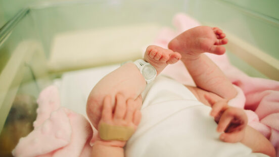 Newborns raised legs with hospital id on ankle.