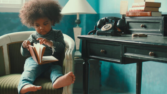 African-American little girl (2-3 years) reading book at home, Bangkok Thailand