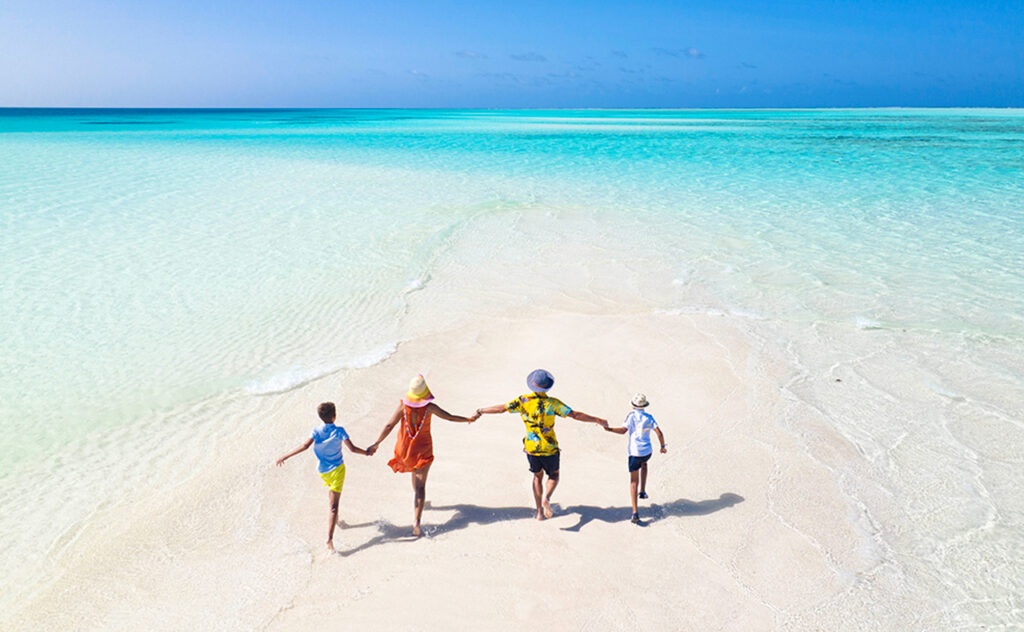 a family plays and has fun on a strip of sand during a splendid sunny day on The Great Barrier Reef