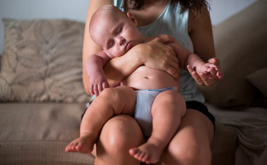 Sleeping infant sitting on mothers lap during a heatwave.