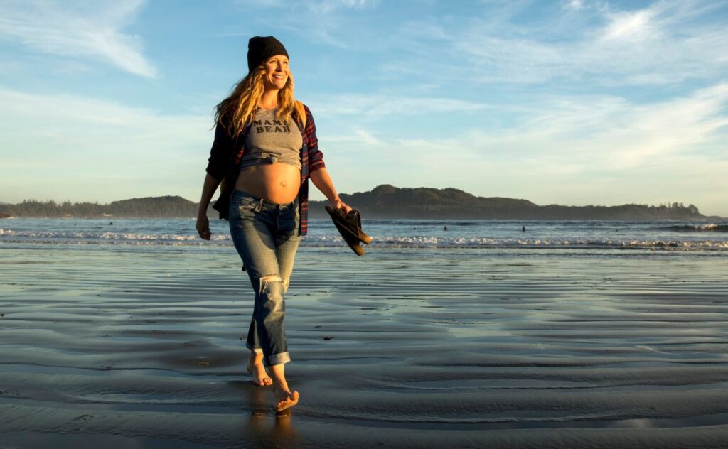 woman pregnant walking along the beach