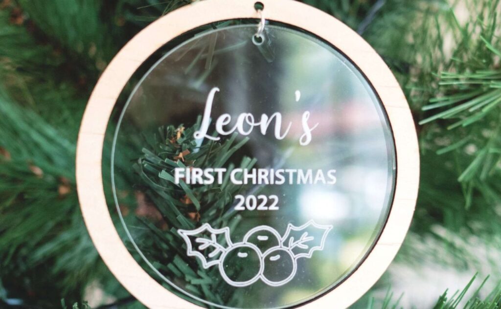 Wood framed acryllic first Christmas bauble hanging on a Christmas tree