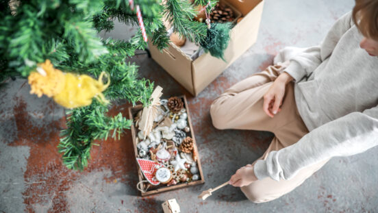 Boy sitting on floor with Christmas decorations. box decorate Christmas tree, top view