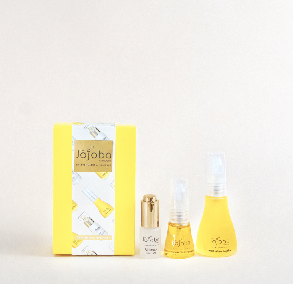 Product shot of Jojoba box and three products in Luminate & Hydrate Holiday Gift Set