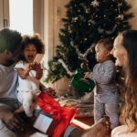 Real life young Australian multi-ethnic family enjoys relaxed time together by the tree in their pyjamas on Christmas morning