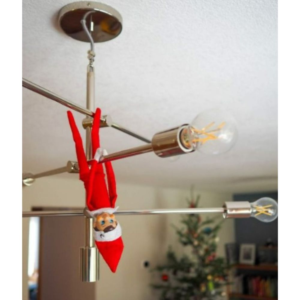 Elf on the shelf hanging from light