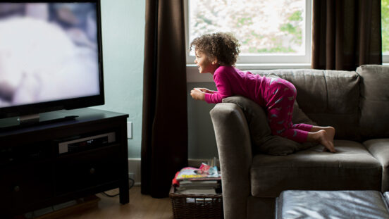Mixed race girl watching television.