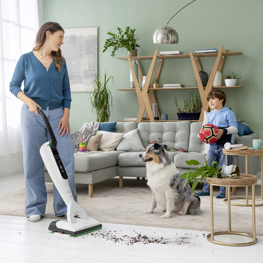 Woman with small child and dog in clean living area using a Kobold VK7