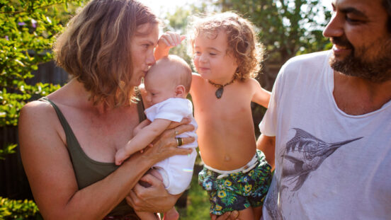 Real family in the garden on a hot day. Mother, father, toddler and baby.